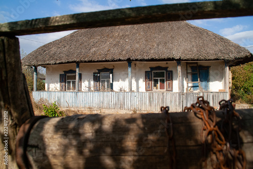 Traditional Ukrainian thatched roof house framed through old rustic wooden well structure in rural setting