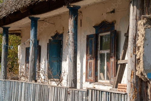 Close-up view of weathered blue wooden porch columns and window shutters on old clay house