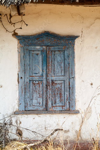 Detailed vertical shot of weathered blue wooden shutters on old rustic whitewashed clay wall