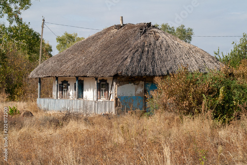Traditional Ukrainian thatched roof mud hut with blue accents in rural landscape
