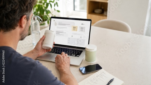 Man using laptop at home office while holding coffee, with focus on wellness