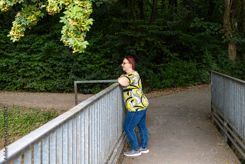Woman standing on bridge railing contemplating nature