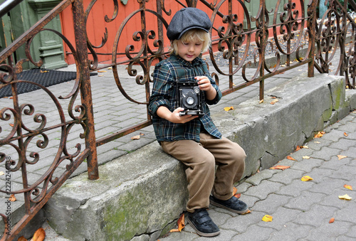 Boy in a flat cap holding an antique camera, vintage photography and historical style