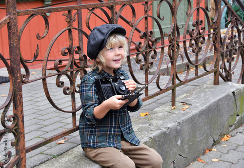 Boy in a flat cap holding an antique camera, vintage photography and historical style