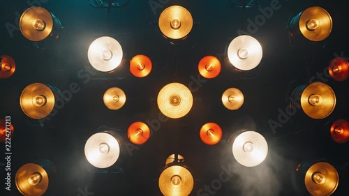 Vintage spotlight array glowing warmly on dark wall creating dramatic stage lighting pattern design
