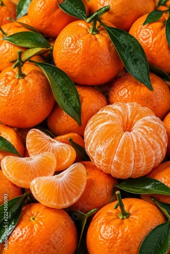 Vibrant orange tangerines with glossy green leaves, some peeled with juicy segments. A fresh and colorful display of citrus fruits for a healthy vibe.