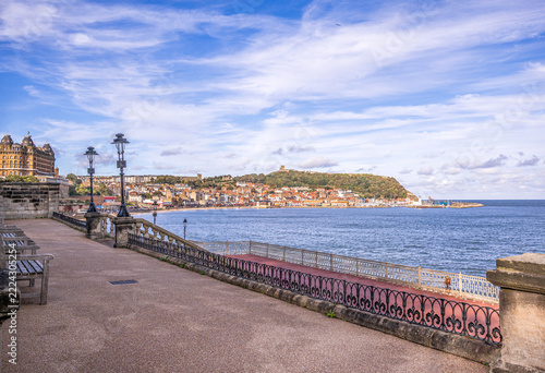 A seaside town with a castle on a hill and railings in the foreground.