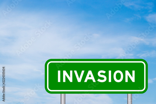 Green color transportation sign with word invasion on blue sky with white cloud background