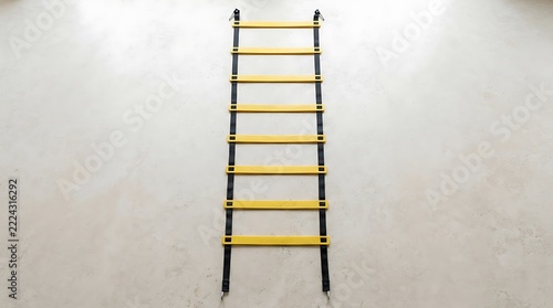 Yellow agility ladder for sports training placed on a light gray concrete floor surface view