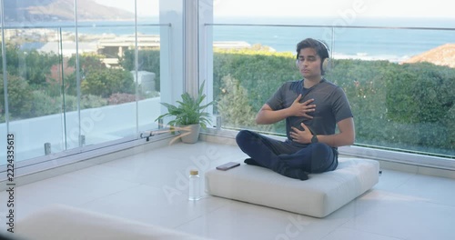 African American man pressing chest, belly following paced breathing on phone by windows to rest