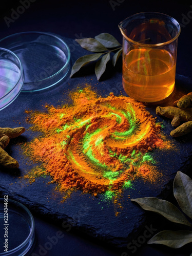 Vibrant turmeric powder with fluorescing elements dark surface, surrounded by leaves and liquid