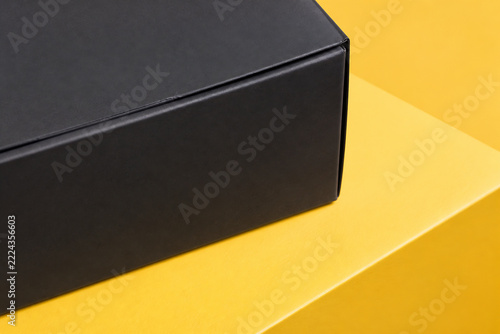 A black rectangular box rests on a bright yellow surface.