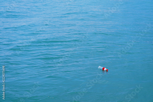 Floating fishing float bobber in calm blue ocean water near shore