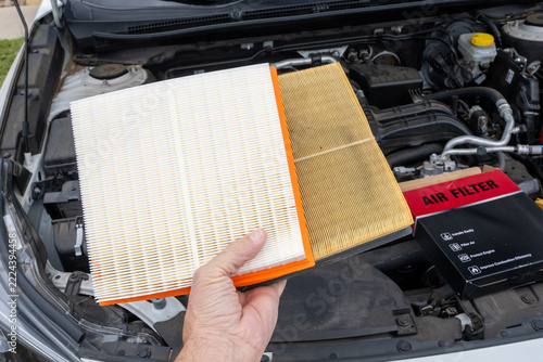 Hand holds clean air filter beside dirty one