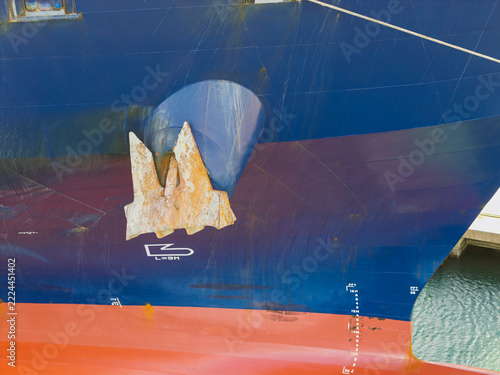 Aerial view of a large ship bow with a prominent anchor, blue hull, red bottom, and draft markings in the United Kingdom.