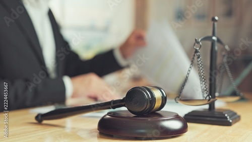 Fotografie Wooden gavel balance scale rest on desk while attorney reviews legal contract documents