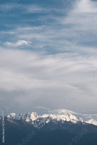Snowy peaks of Talgar Peak in Almaty, Kazakhstan under vast cloudy sky in daylight. Minimalist commercial background for travel, lifestyle, and outdoor adventure with copy space.