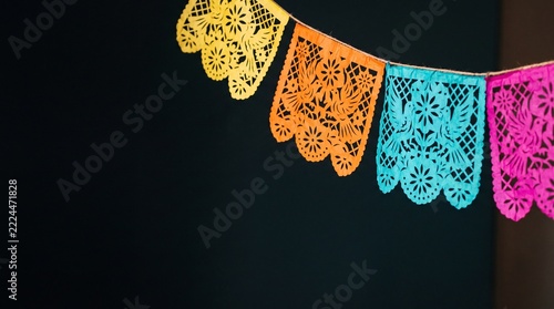 Día de Muertos celebration background featuring colorful traditional papel picado banners hanging against a dark background with copy space