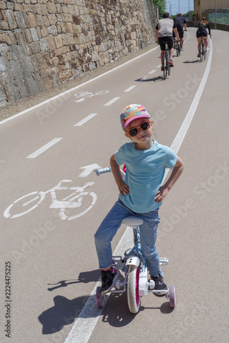 Child learning to ride bike with training wheels