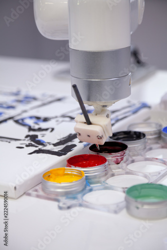 A mechanical manipulator dips paintbrush into paint container