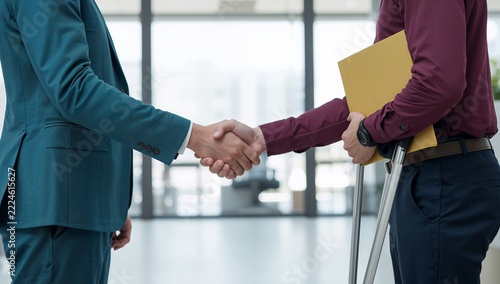 Professional Handshake Between Businessmen with One Person Using Crutches in Modern Office, Diversity and Inclusion Concept