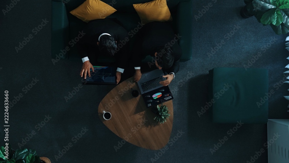 Naklejka premium Top down aerial view of professional project manager walking to workspace and working on tablet while colleague holding laptop and support his performance. Business team working together. Directorate.