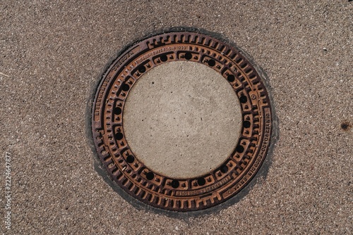 Fotografie Round manhole cover on asphalt pavement
