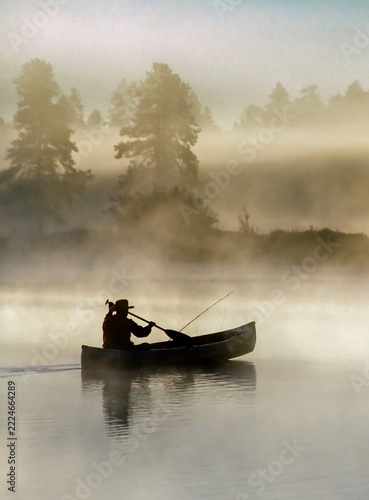 A man paddeling a canoe on a foggy morning on Lake Thalorope near Sisters, Oregon