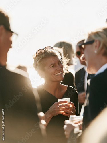 Social connection at a sunny reception with smiling woman holding a drink