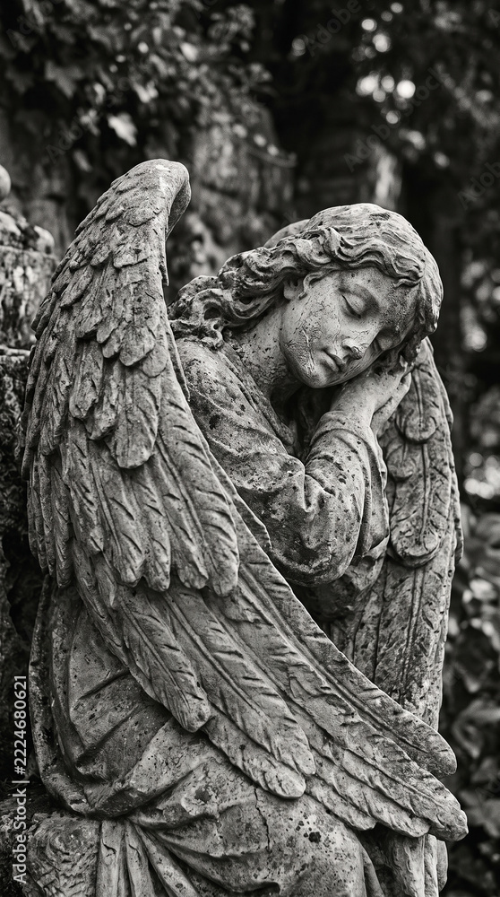 Fototapeta premium Sculpted gray stone guardian angel sleeping peacefully, aged stone surface, softly blurred dark gray background, muted monochromatic palette, minimalist religious aesthetic.