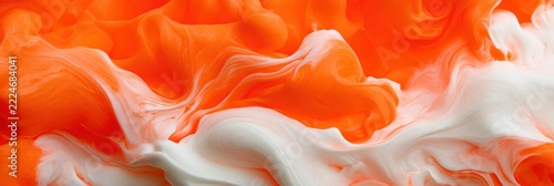 Bright day-glo orange mixes with white cream forming a unique fluid texture on a flat surface during daytime