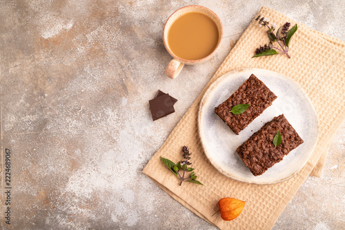 Chocolate cheese cake with cup of coffee on brown concrete, copy space, top view.