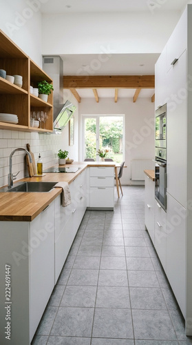 Modern galley kitchen with white cabinets wooden countertops and beams bright and airy
