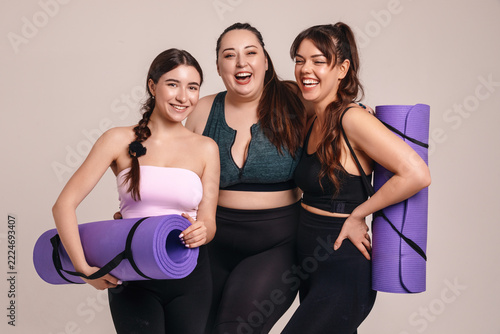 Fotografie Attractive women athletes smiling in coordinated workout outfits with yoga mats