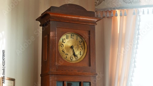 Vintage tall wooden grandfather floor clock featuring an ornate gold dial with black hands