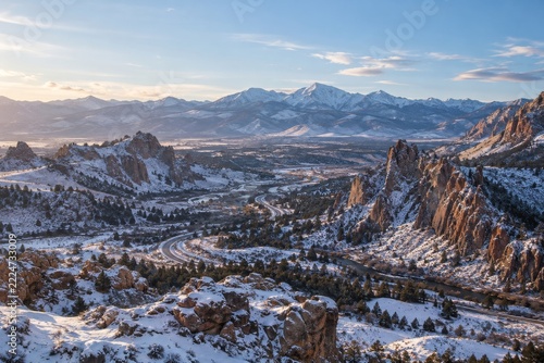 Elevated winter valley view with snowy rock formations and winding mountain r...