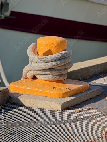 Rope wrapped around orange mooring bollard