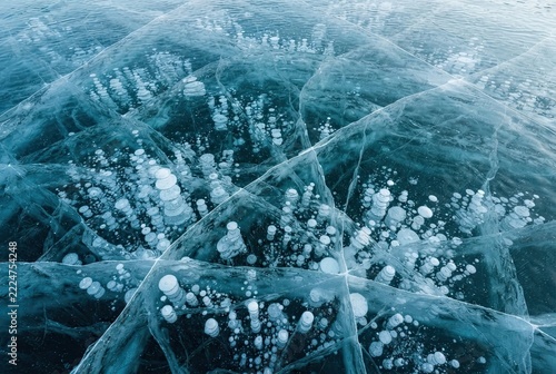 Frozen air bubbles trapped inside thick transparent lake ice creating intricate crystalline patterns during the cold winter season.