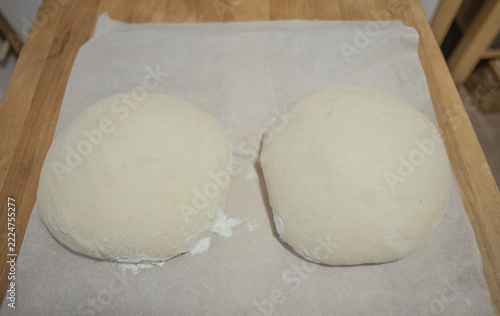 Top view of two raw yeast dough balls resting on baking paper
