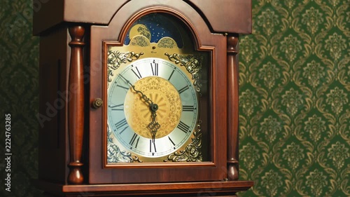 Close up of an antique wooden grandfather clock face. Traditional brass dial with Roman numerals