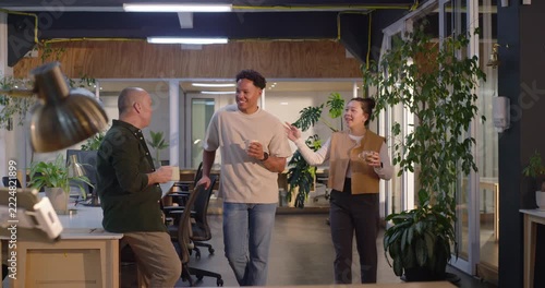 Diverse coworkers chatting, sipping coffee on break in office after center man walking in