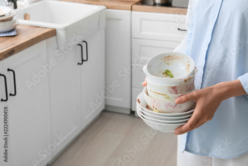 Household chores and domestic labor, person holding a stack of dirty dishes i...
