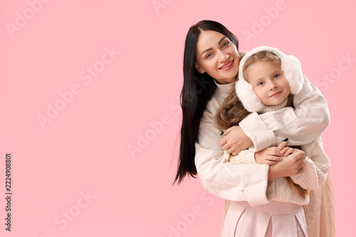 Young mother and her little daughter on pink  background