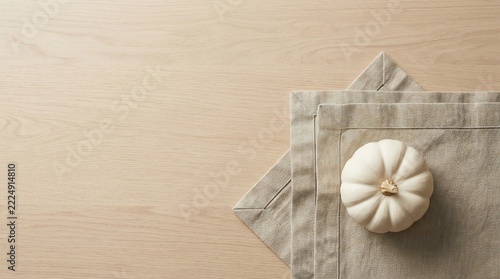 White pumpkin on linen napkin over light wooden table top view