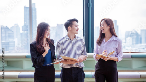 Asian Business Team Collaborating and Discussing Ideas in a Modern Office with City View