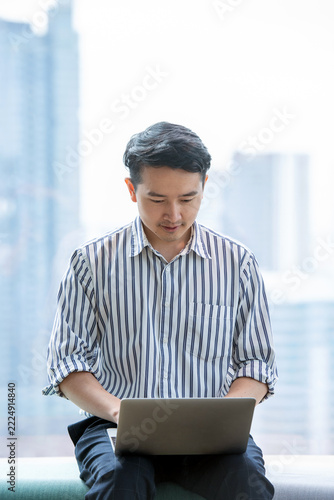 Asian Businessman Using Laptop in Modern Office, Online Work, Technology and Business Success