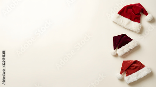 Three red santa claus hats arranged on a light background for christmas holiday marketing designs