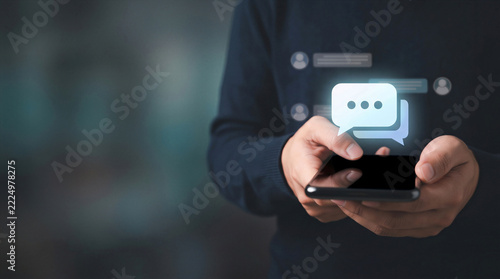 Man typing on smartphone with chat bubble icons for online messaging and customer support