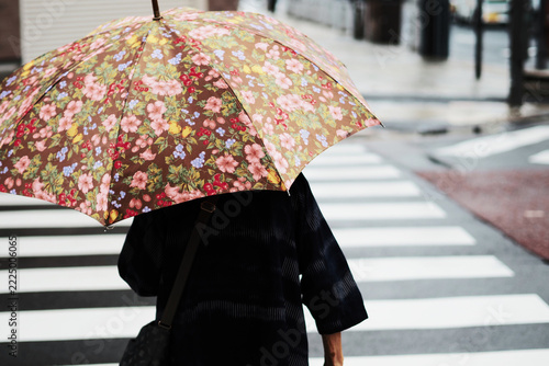 雨の日に横断歩道を渡る高齢者の後ろ姿