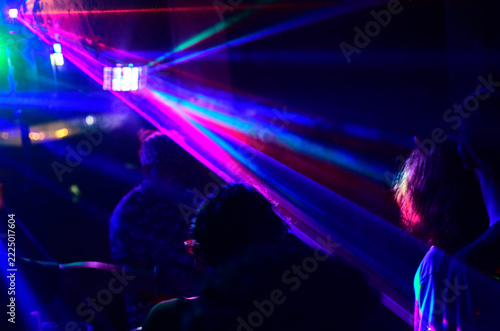 People dancing under multicolored laser lights in a nightclub